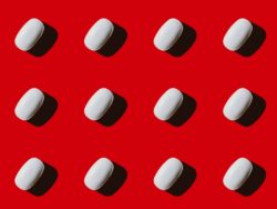 White pills on red background