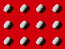 White pills on red background