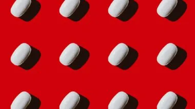 White pills on red background