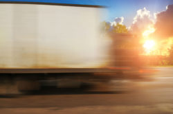 White big boxed truck driving fast on evening countryside road