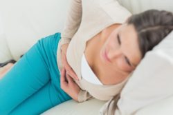 Woman in blue pants with stomach pain