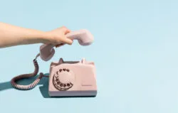 A woman's hand hanging up a phone
