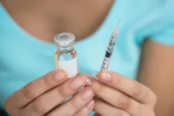 Woman holding a vaccine bottle and syringe