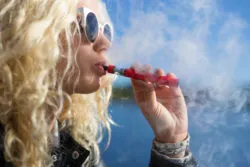 A woman uses a vape pen.
