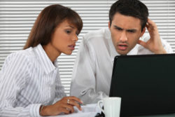 Annoyed couple looks at bank fees on computer