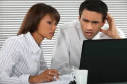 Annoyed couple looks at bank fees on computer
