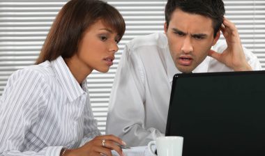 Annoyed couple looks at bank fees on computer