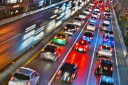 Cars drive on a highway at night.