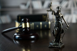 Justice statue in front of gavel and law books