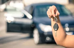 Man holds rental car key and wonders if a credit card will cover rental car insurance.