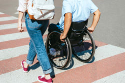 Man in wheelchair and woman on crosswalk