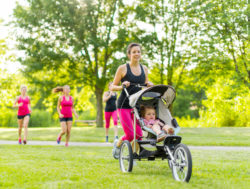 Mother runs in park pushing baby in joggng stroller
