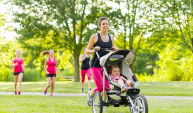 Mother runs in park pushing baby in joggng stroller