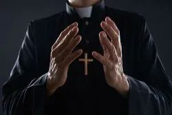 priest praying with open arms for sex abuse victims