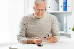 Senior man with Type 2 diabetes checks blood sugar and stays vigilant about signs of flesh eating bacteria infection.