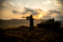 Soldier with gun in front of tank