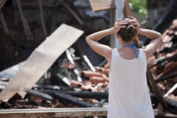 Woman in front of burned house