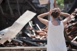Woman in front of burned house