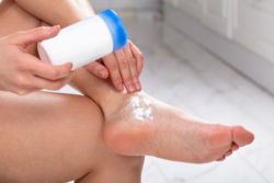 Woman puts powder on foot
