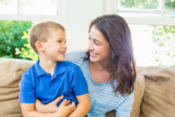 A boy and a woman sit on a sofa.