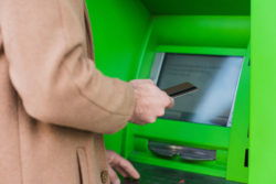 A person uses a green ATM.