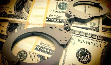 Fraud concept with handcuffs on money