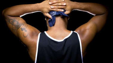 A man holds his hands behind his head.