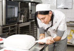 A pastry chef decorates a cake.
