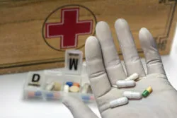 Gloved hand putting pills in organizer