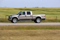 Truck driving on road in front of field