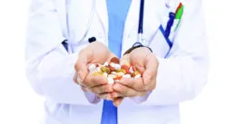 A doctor holds a handful of pills.