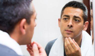 Man examining skin in mirror