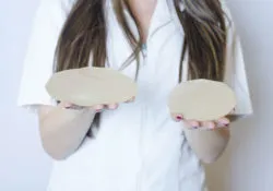 A nurse holds two textured breast implants.
