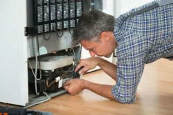 A man repairs a refrigerator.