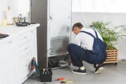 repairman fixing refrigerator