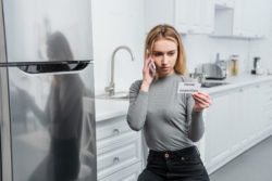Woman phoning repairman because her LG refrigerator not cooling.