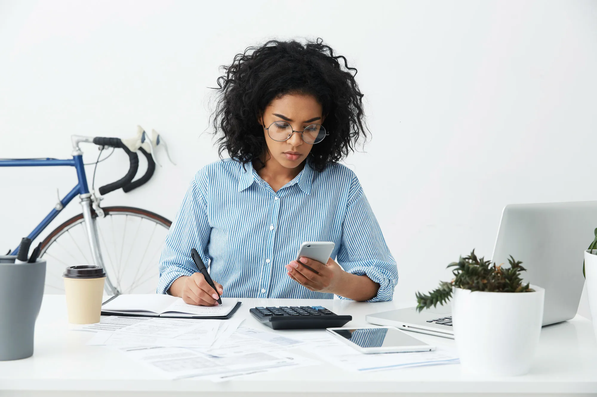 A woman at a desk looks at her phone.