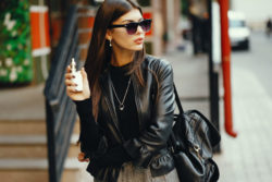 A woman smokes an e-cigarette on a sidewalk.