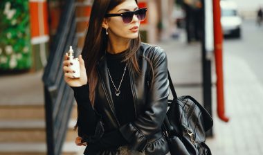A woman smokes an e-cigarette on a sidewalk.