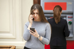 A concerned woman steps away from an ATM.