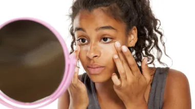 A woman uses a mirror to apply makeup.