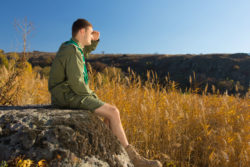 A Boy Scout sits on a ledge.