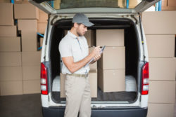 A delivery driver reads from a clipboard.