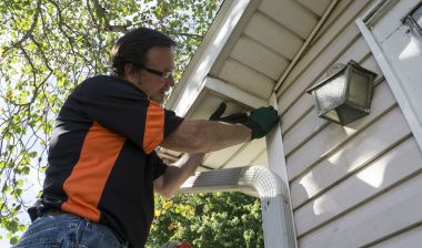 A man fixes exterior trim on a house.