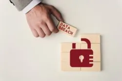 Partial view of man holding brick with 'data breach' lettering