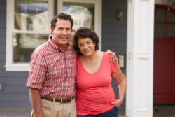 A couple stands in front of a house.