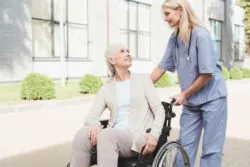 A doctor helps a woman in a wheelchair.