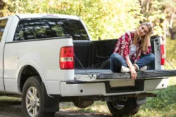Woman sitting on tailgate of pickup truck