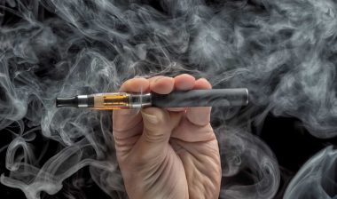 Hand holding an electronic cigarette over a dark background