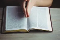 A woman's hands shown in prayer with opened bible
